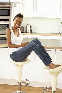 Young Woman Relaxing Sitting In Modern Kitchen 