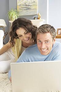 Couple Using Laptop Relaxing Laying On Rug At Home