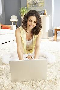 Woman Using Laptop Relaxing Sitting On Rug At Home 