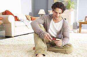 Young Man Looking At Photograph On Digital Camera At Home 