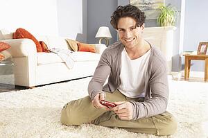 Young Man Looking At Photograph On Digital Camera At Home 