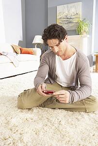 Young Man Looking At Photograph On Digital Camera At Home 