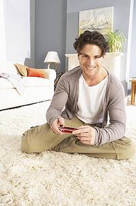 Young Man Looking At Photograph On Digital Camera At Home 