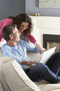 Couple Using Laptop Relaxing Sitting On Sofa At Home
