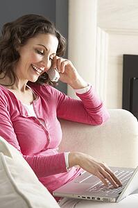Woman Using Laptop Relaxing Sitting On Sofa At Home Talking On Phone
