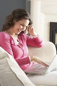 Woman Using Laptop Relaxing Sitting On Sofa At Home Talking On Phone