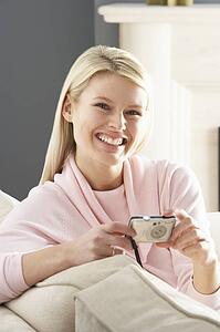 Young Woman Taking Photograph On Digital Camera At Home 