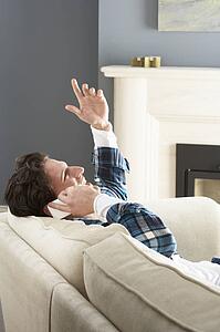 Man Relaxing Sitting On Sofa At Home Talking On Phone