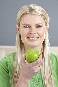 Woman Relaxing On Sofa Eating Apple At Home