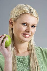 Woman Relaxing On Sofa Eating Apple At Home