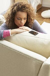 Woman Sitting On Sofa Wating For Mobile Phone At Home 