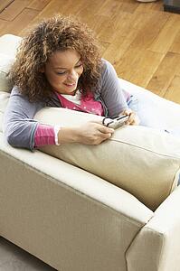 Woman Looking At Pictures On Digital Camera Relaxing Sitting On Sofa At Home
