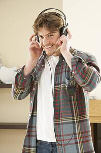 Young Man Relaxing Sitting On Sofa Listening to Music At Home On Headphones