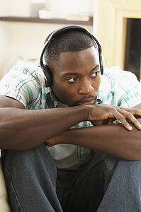 Young Man Relaxing Sitting On Sofa Listening to Music At Home On Headphones
