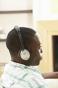 Young Man Relaxing Sitting On Sofa Listening to Music At Home On Headphones