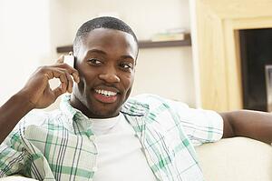 Young Man Relaxing Sitting On Sofa At Home Talking On Phone