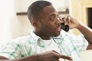 Young Man Relaxing Sitting On Sofa At Home Talking On Phone