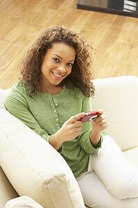 Woman Looking At Pictures On Digital Camera Relaxing Sitting On Sofa At Home