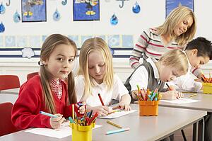 Group Of Primary Schoolchildren And Teacher Having lesson In Classroom