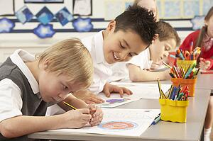 Group Of Primary Schoolchildren In Classroom Working At Desks