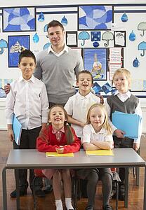Portrait Of Group Of Primary Schoolchildren And Teacher Sitting At Desk In Classroom