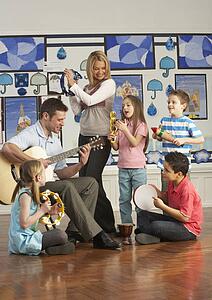 Teachers Playing Guitar With Pupils Having Music Lesson In Classroom