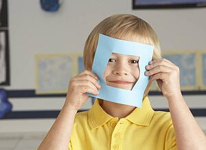 Male Primary School Cutting Out Paper Shapes In Craft Lesson