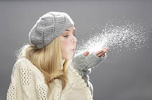 Teenage Girl Wearing Warm Winter Clothes And Hat Blowing Snow In Studio