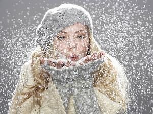 Teenage Girl Wearing Warm Winter Clothes And Hat Blowing Snow In Studio