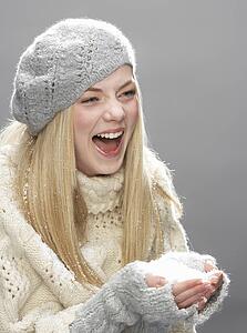 Teenage Girl Wearing Warm Winter Clothes And Hat Blowing Snow In Studio