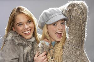 Two Fashionable Teenage Girls Wearing Cap And Knitwear In Studio