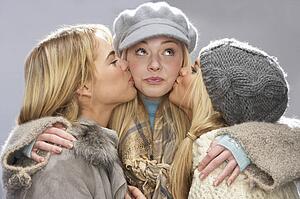 Three Teenage Girls Wearing Cap And Knitwear In Studio Giving Each Other Kiss