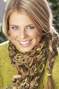 Fashionable Woman Wearing Knitwear And Scarf In Studio In Front Of Christmas Tree