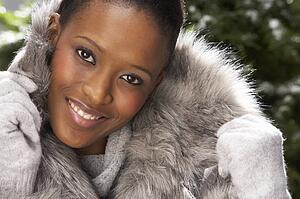 Fashionable Woman Wearing Fur Coat In Studio In Front Of Christmas Tree