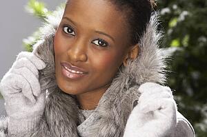 Fashionable Woman Wearing Fur Coat In Studio In Front Of Christmas Tree