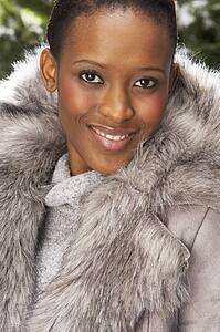 Fashionable Woman Wearing Fur Coat In Studio In Front Of Christmas Tree