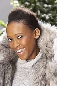 Fashionable Woman Wearing Fur Coat In Studio In Front Of Christmas Tree