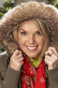 Fashionable Woman Wearing Parka Coat And Scarf In Studio In Front Of Christmas Tree