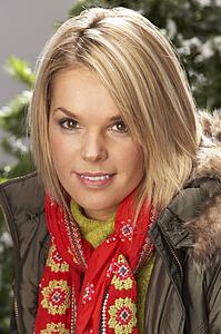 Fashionable Woman Wearing Parka Coat And Scarf In Studio In Front Of Christmas Tree