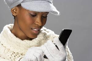 Fashionable Woman Wearing Knitwear And Cap In Studio Using Mobile Phone