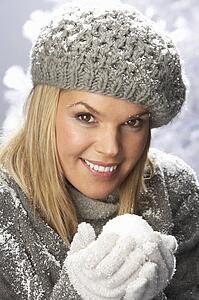 Fashionable Woman Wearing Cap And Knitwear Holding Snowball In Studio In Front Of Christmas Tree