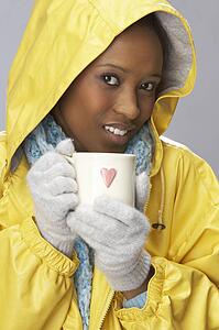Young Woman Drinking Hot Drink Wearing Yellow Raincaot
