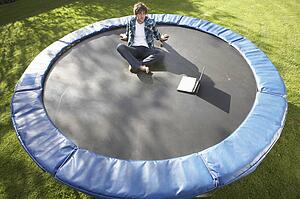 Young Man Relaxing On Trampoline With Laptop