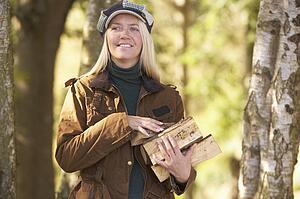 Woman Outdoors In Autumn Woodland Gathering Logs
