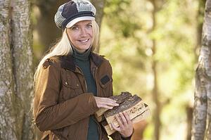Woman Outdoors In Autumn Woodland Gathering Logs