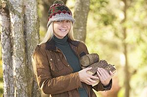 Woman Outdoors In Autumn Woodland Gathering Logs