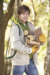 Man Outdoors In Autumn Woodland Gathering Logs