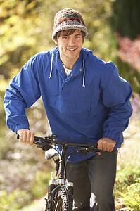 Portrait Of Young Man With Cycle In Autumn Park