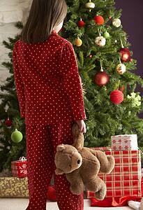 Young Girl Standing With Teddy Bear In Front Of Christmas Tree