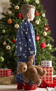 Young Boy Holding Teddy Bear In Front Of Christmas Tree